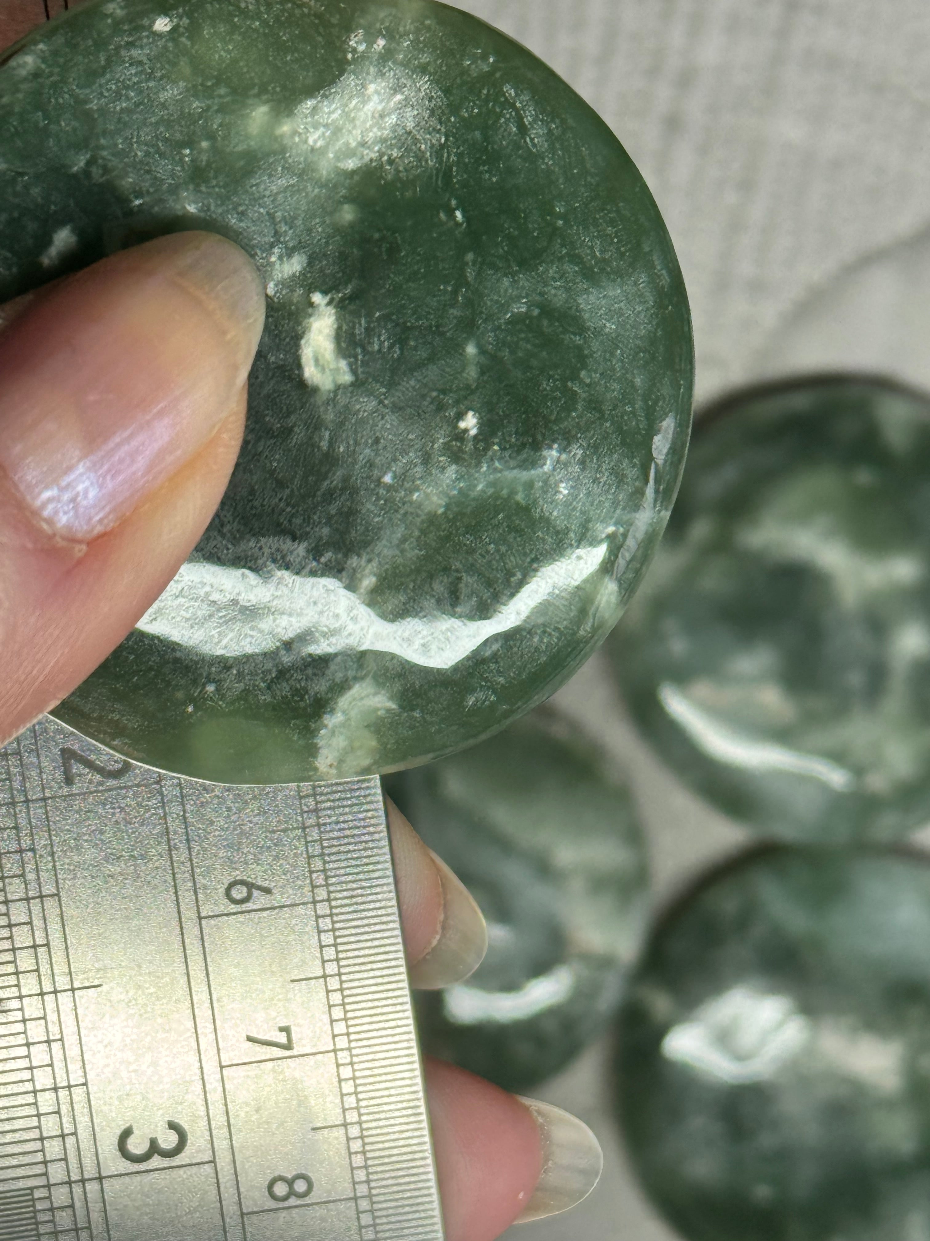 Green stone being held with a ruler for size reference