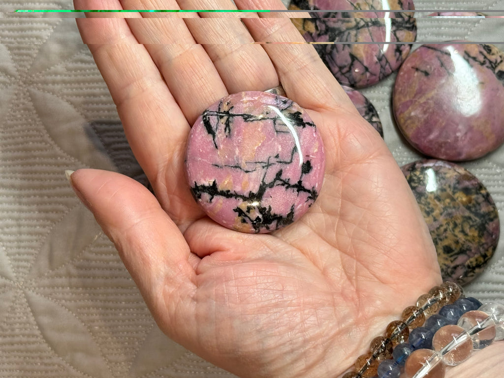 Hand holding a pink marbled stone with more stones in the background