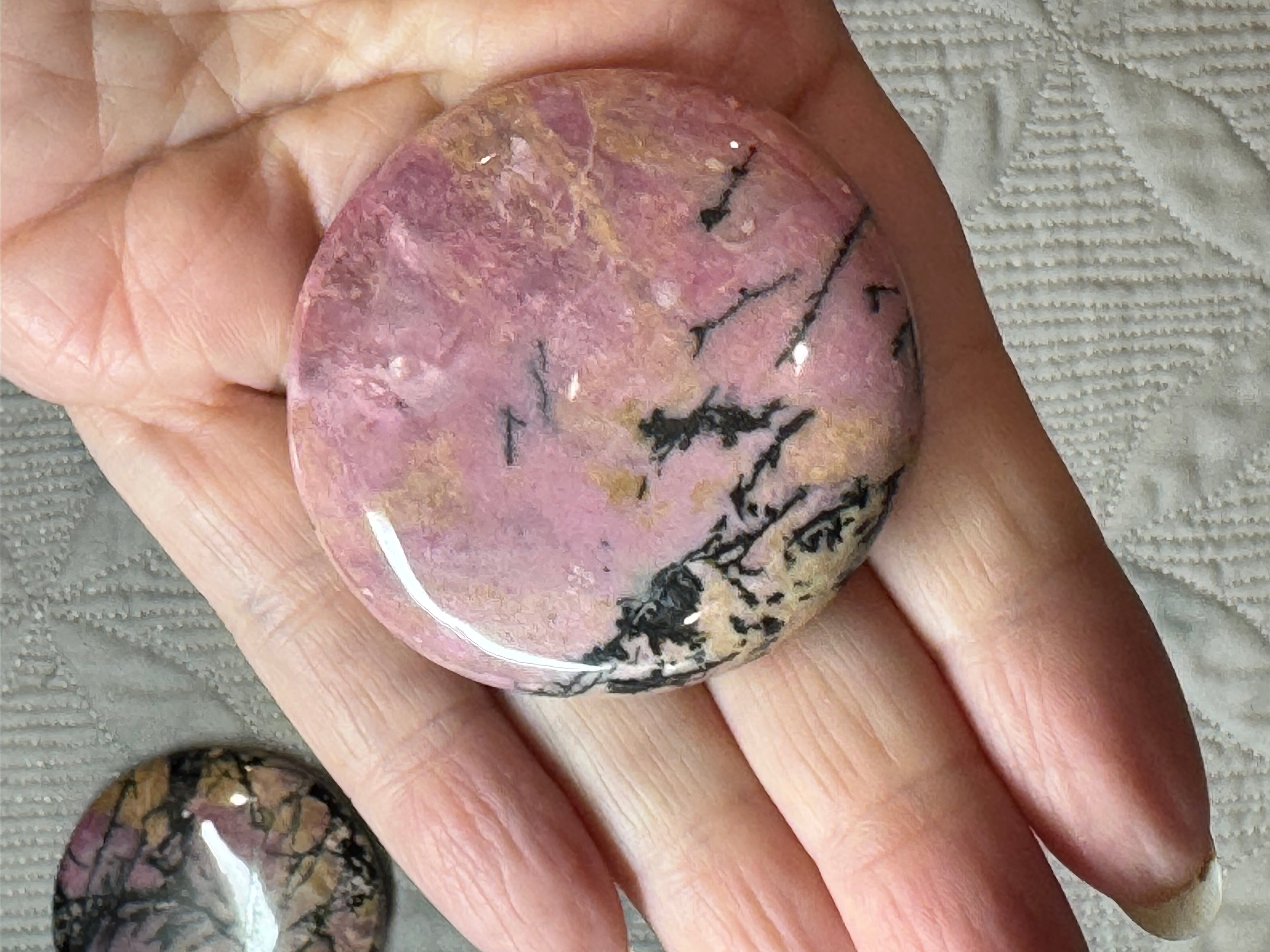 Hand holding a pink and black marbled stone