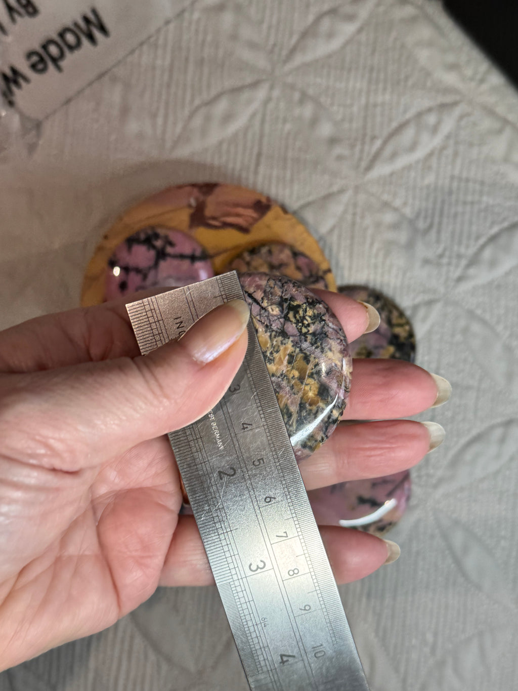 Hand holding a ruler over a crystal with a textured surface in the background