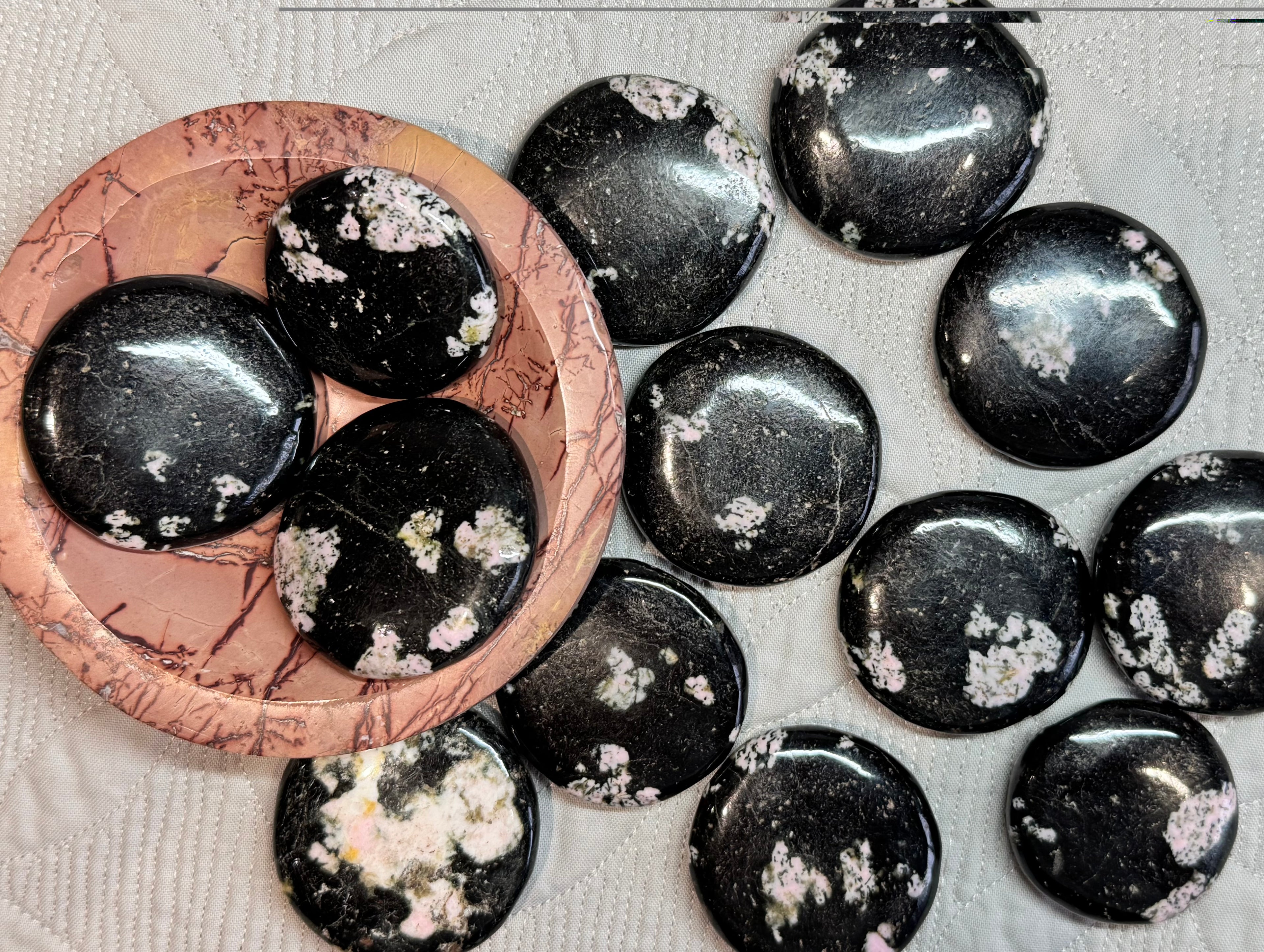 Black stones with white floral patterns on a textured surface
