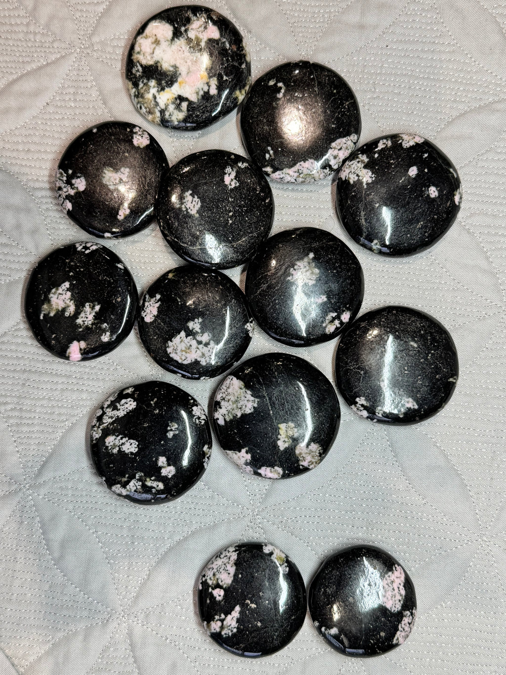 Black stones with white speckles on a textured white surface