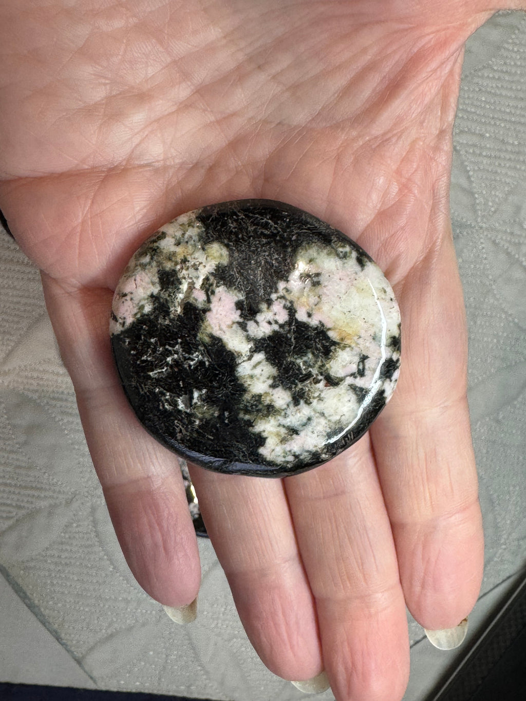 Round stone with black and white pattern held in a hand