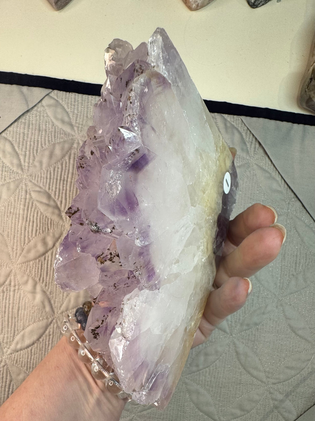 Amethyst crystal held by a hand on a textured surface