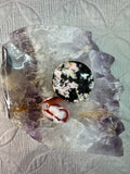 Decorative stone with a circular black and white pattern on a textured gray background
