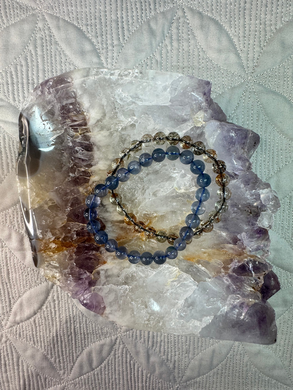 Blue beaded bracelet on a crystal bowl with a textured white  backgroundbackground