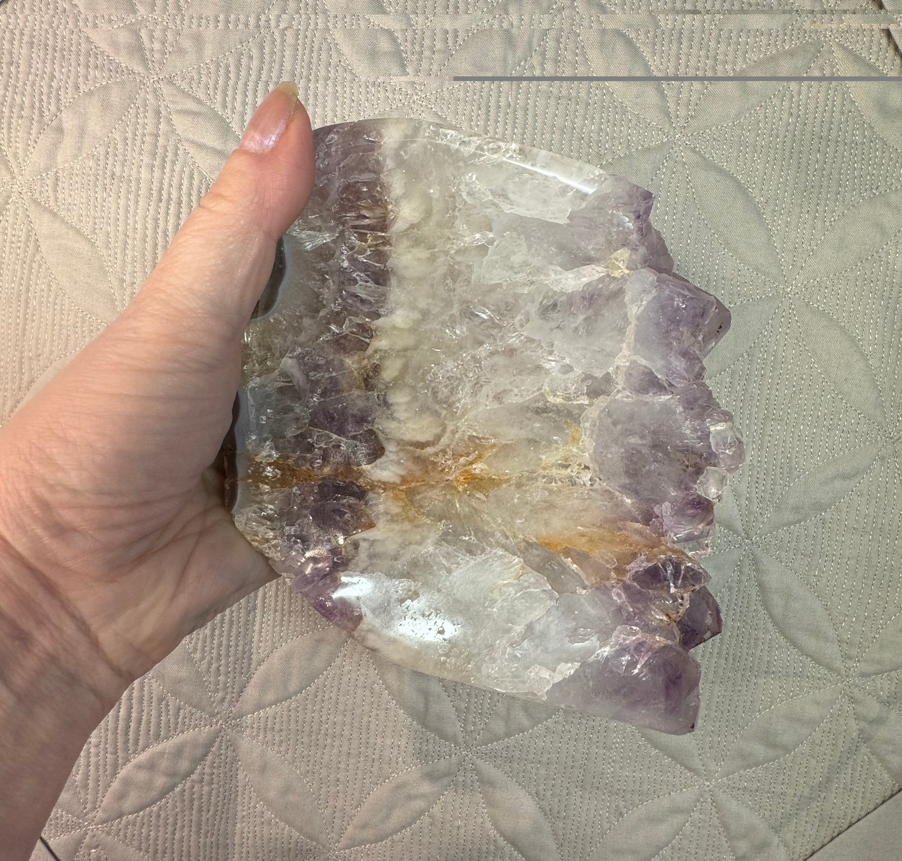 Hand holding a large crystal with a textured surface background