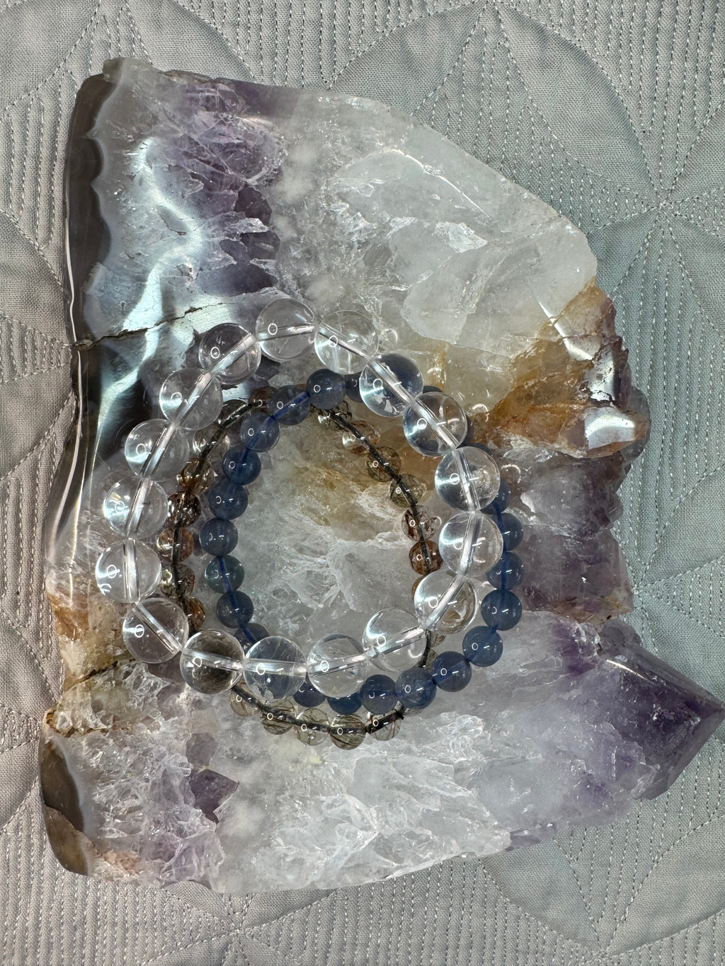 Two bracelets on a crystal bowl with a textured fabric background