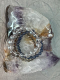 Two bracelets on a crystal bowl with a textured fabric background