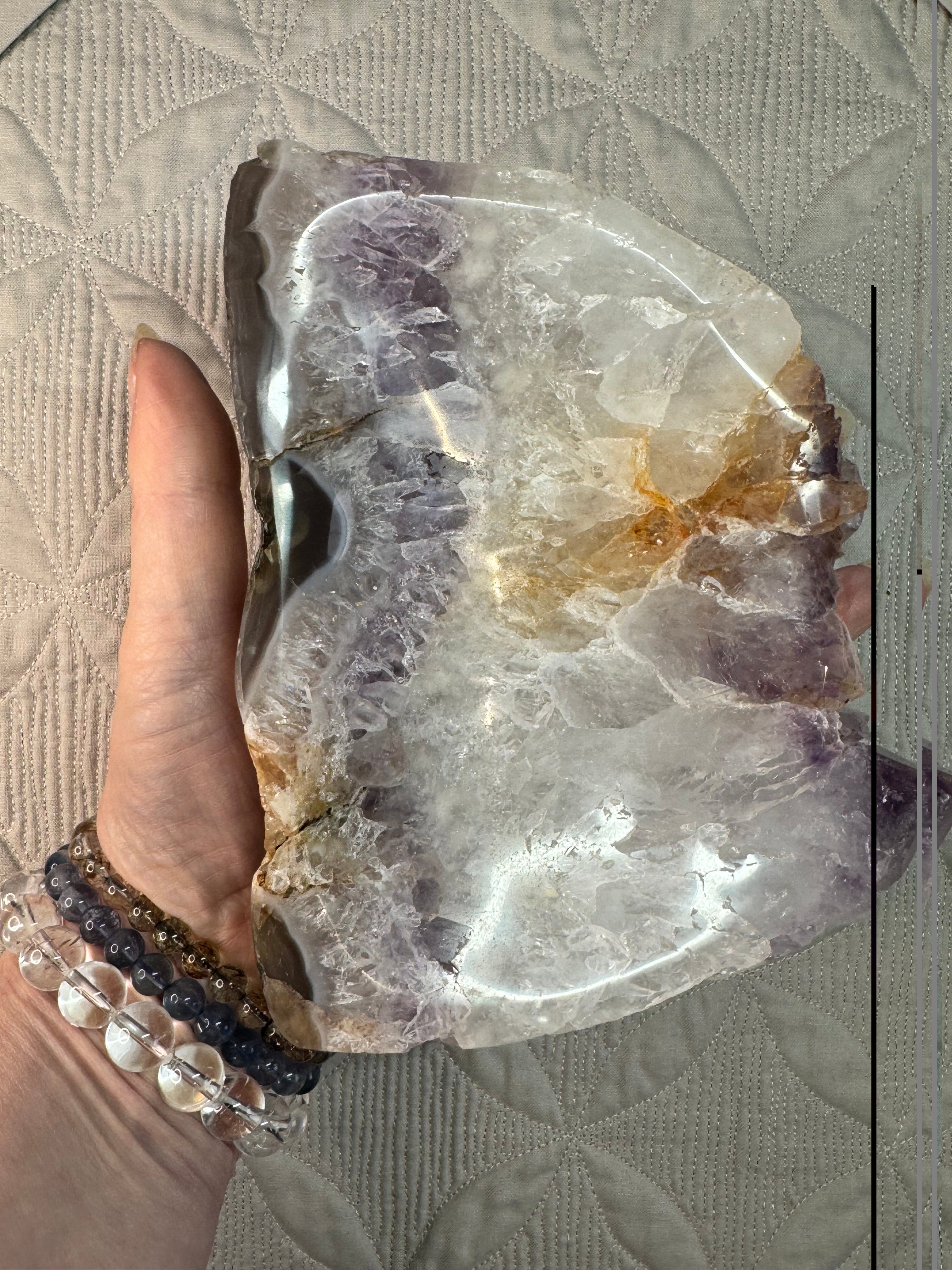 Raw crystal rock held by a hand on a textured surface