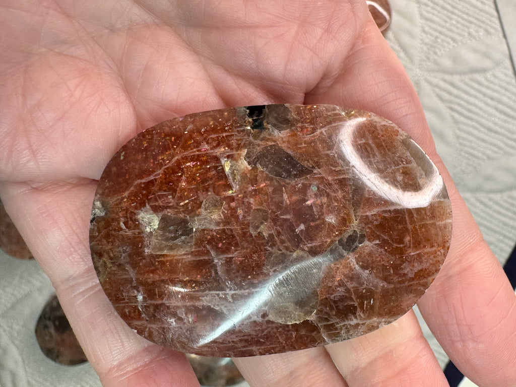 Brown stone with white veins held in a hand on a wooden surface