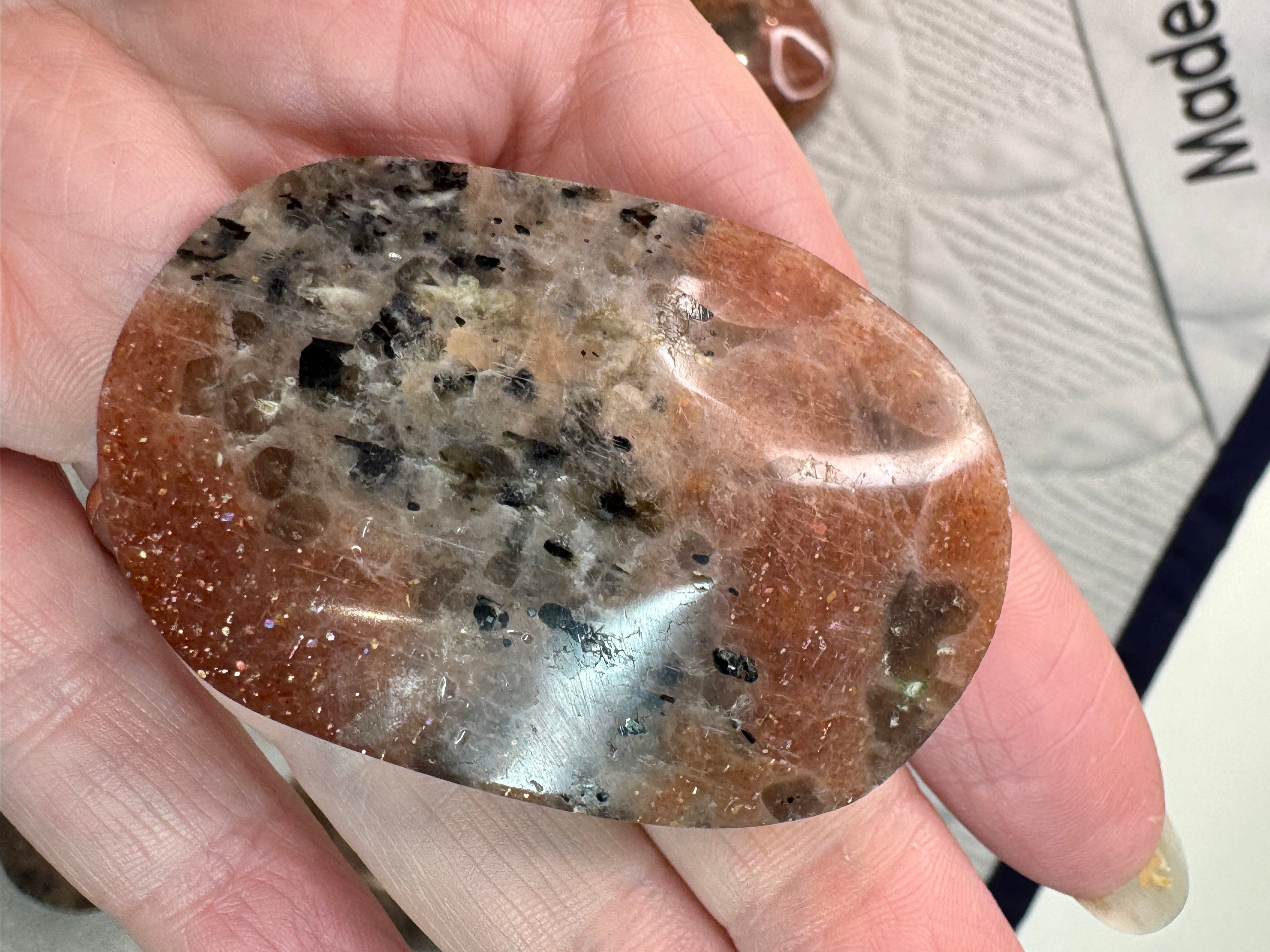 Hand holding a polished brown and gray stone