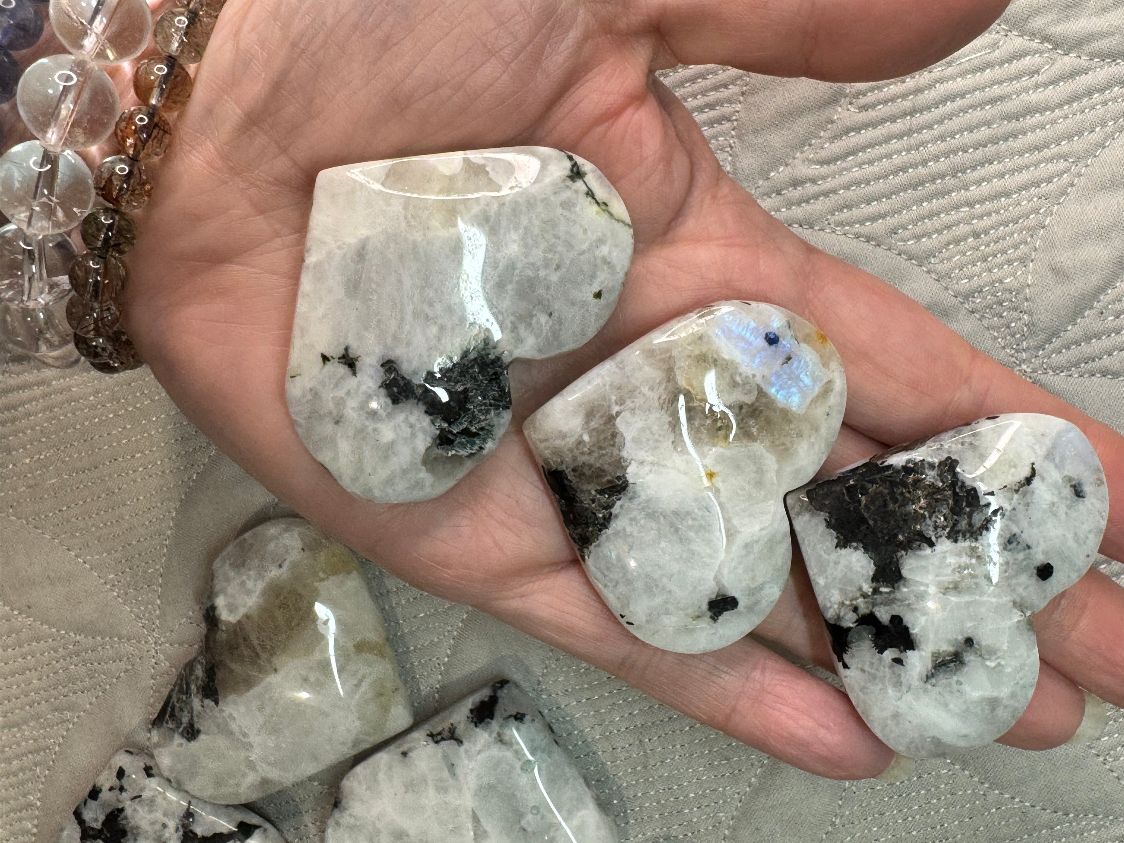 Heart-shaped crystal stones held in a hand with a textured surface background