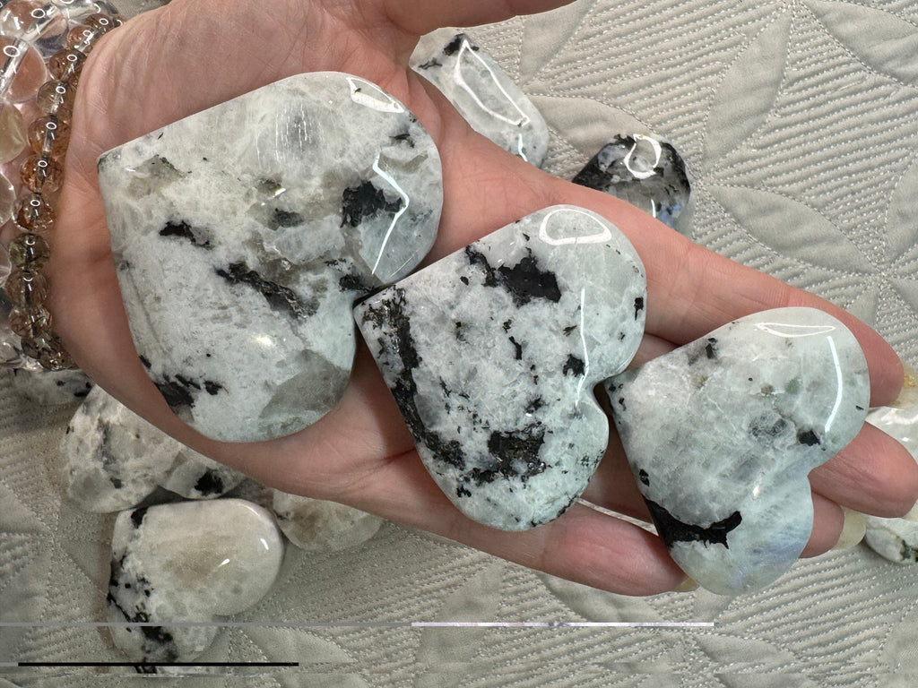 Heart-shaped crystal stones held in a hand with a textured surface background
