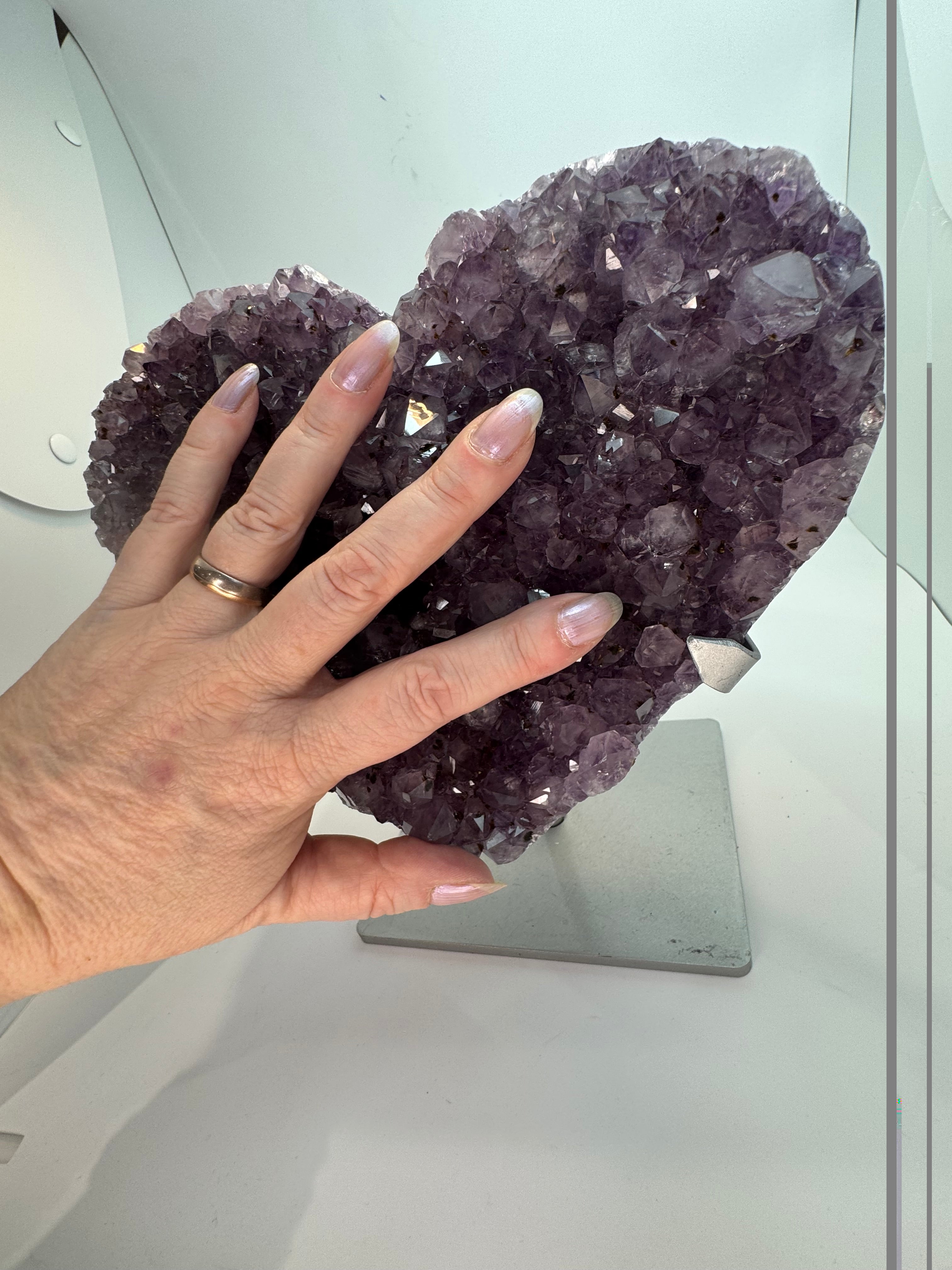 purple crystal heart with a hand in front of it, showing size.