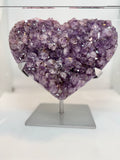 Heart-shaped purple crystal on a stand against a white background
