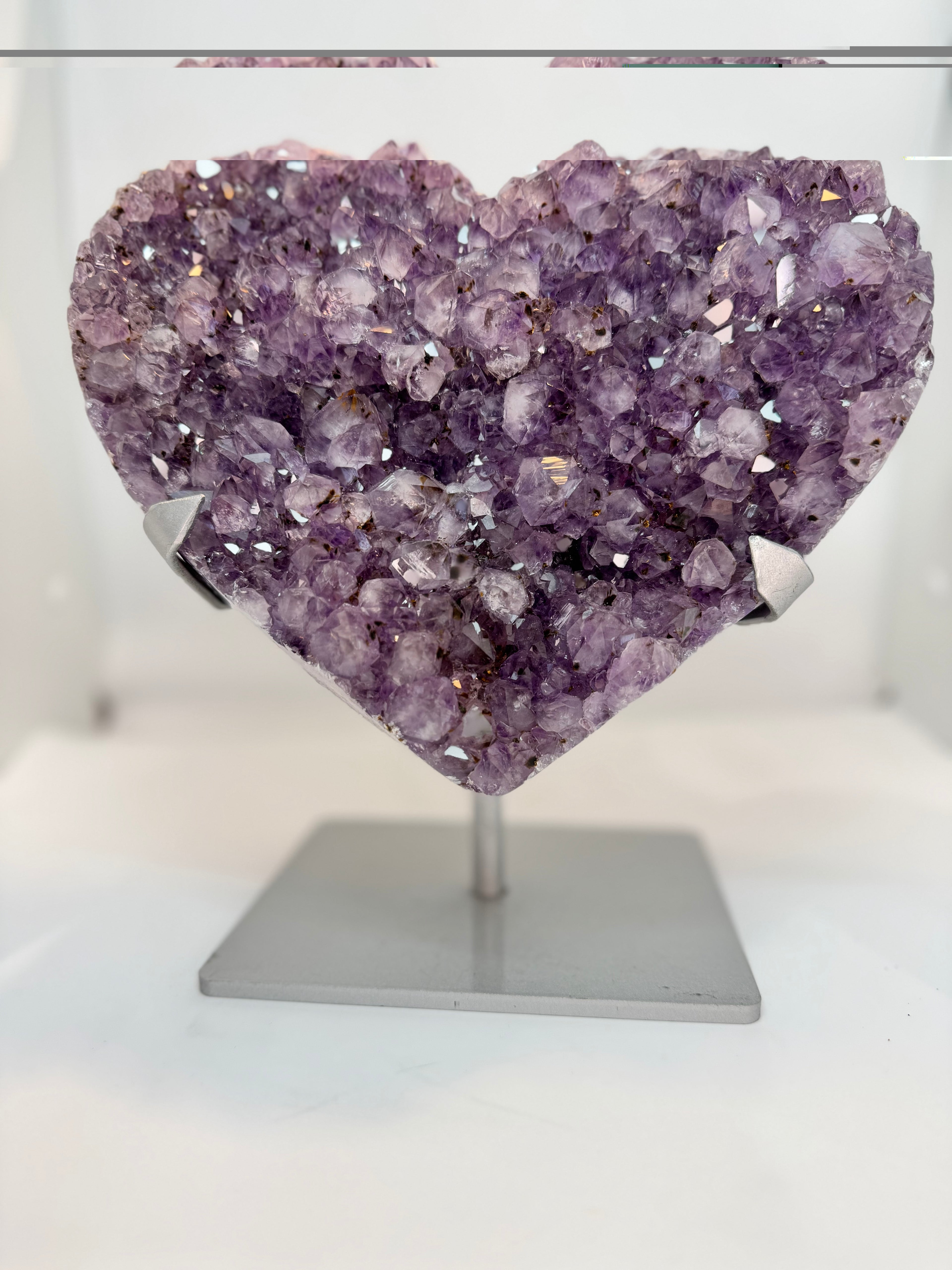 Heart-shaped purple crystal on a stand against a white background