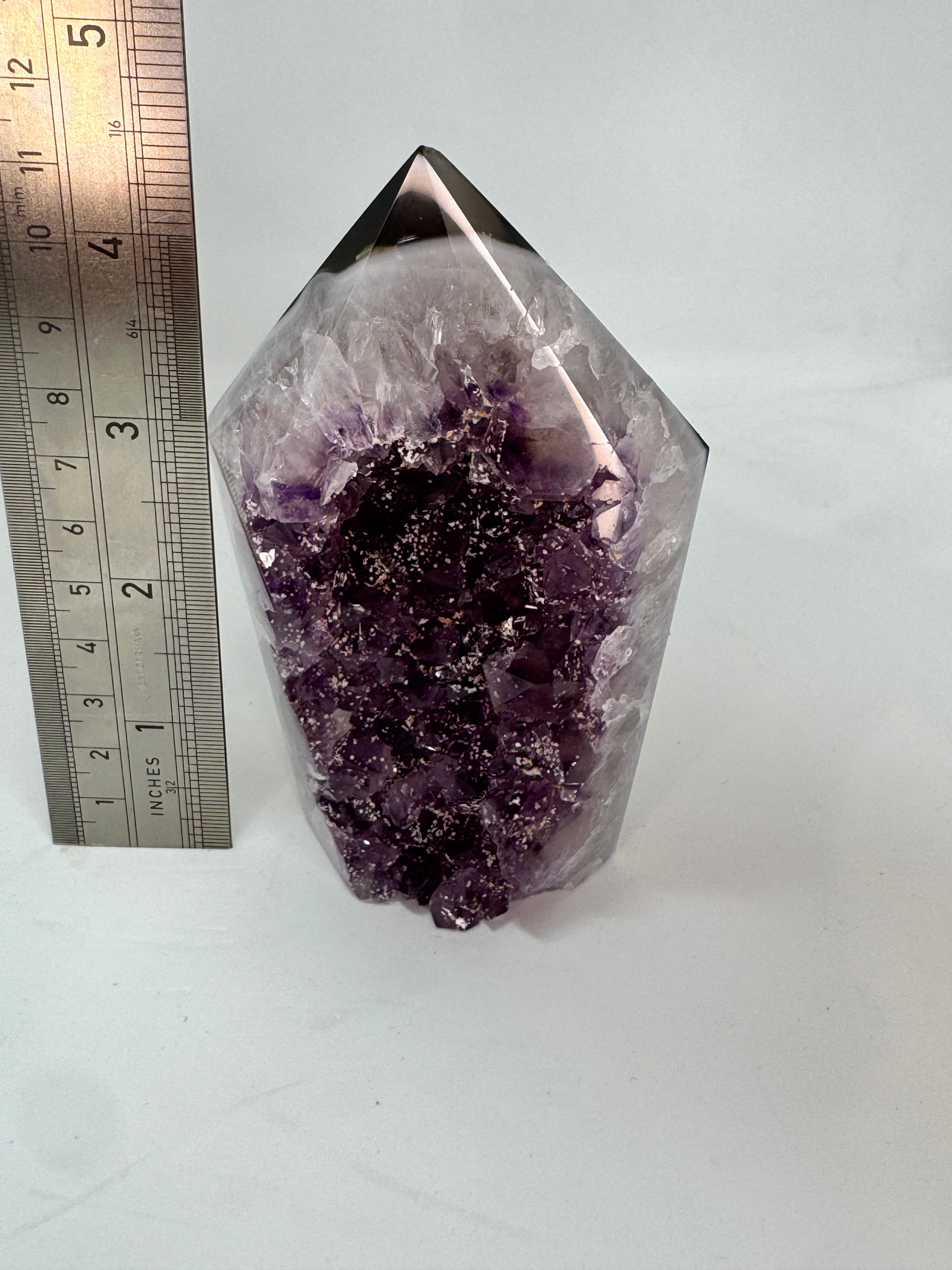 Amethyst crystal with a ruler for scale on a white background