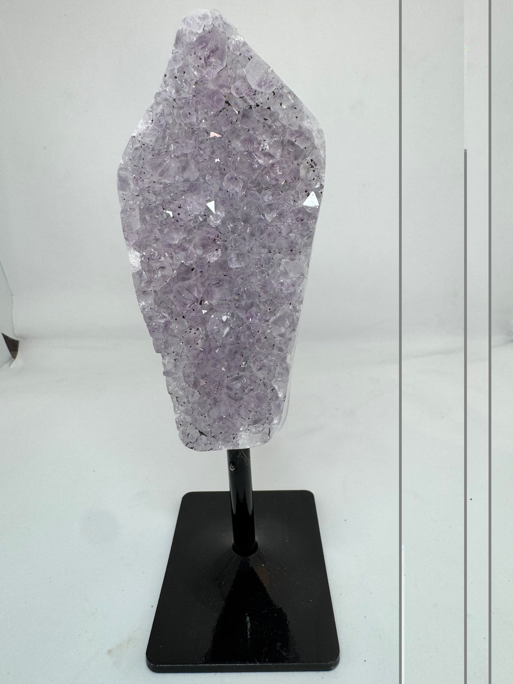 Lavander crystal on a black stand on a white background