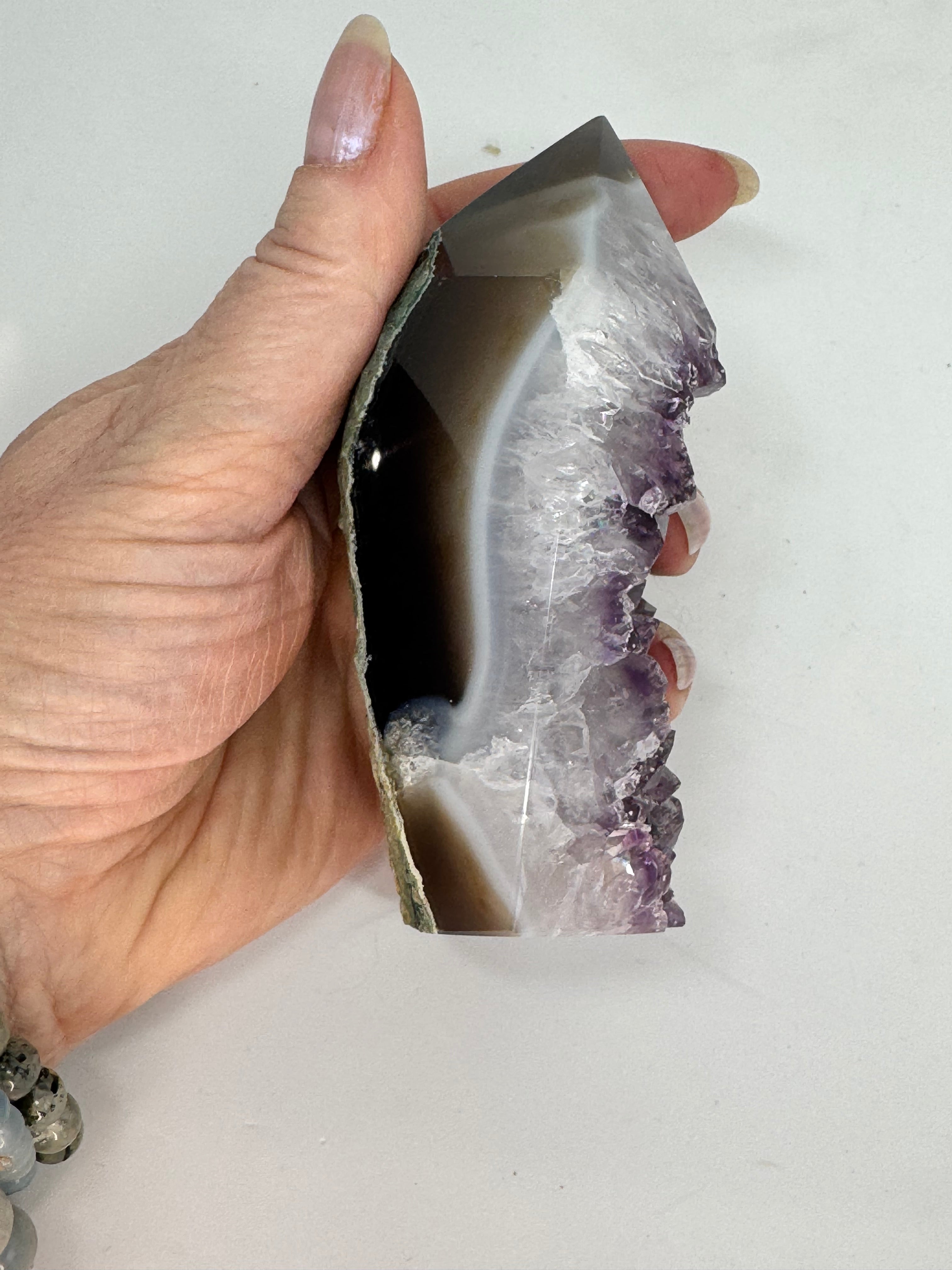 Hand holding a cut open amethyst geode against a white background