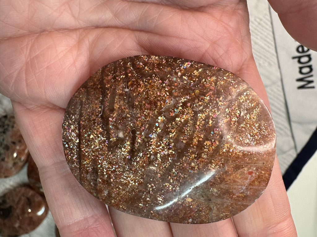 Brown gemstone held in a hand with a blurred background