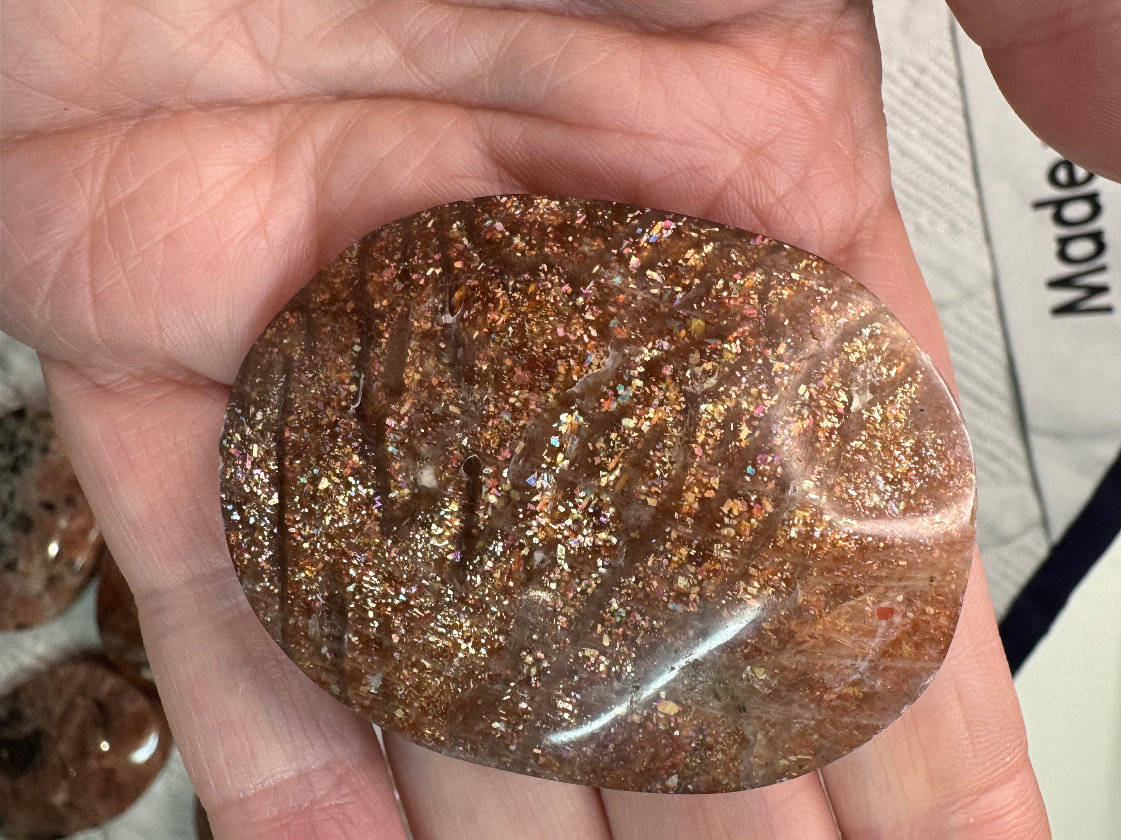 Brown gemstone held in a hand with a blurred background
